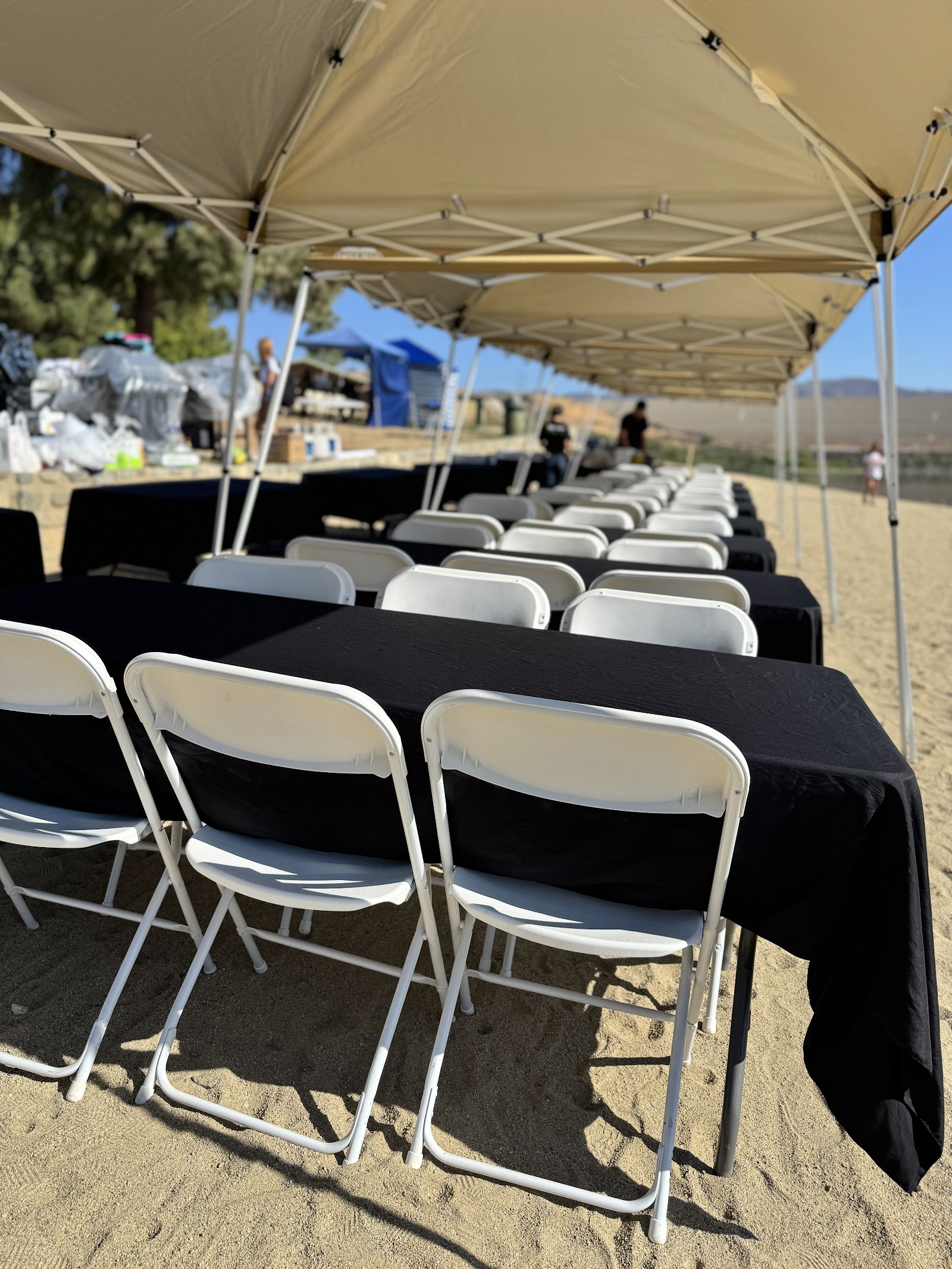 White folding chairs and black-covered tables under pop-up tents